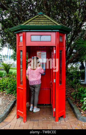 Eine Frau mit einem öffentlichen Phonebooth, Whangarei, North Island, Neuseeland Stockfoto
