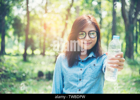 Schöne Mädchen trinkt Wasser aus einer Flasche auf der Natur Stockfoto