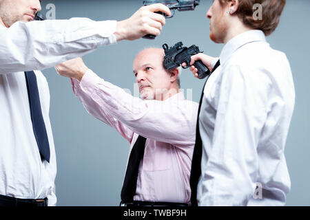 Business Stand-off oder Patt Konzept mit drei Unternehmer stehen in einem Kreis, die Gewehre an jeden anderen Köpfe jeder bestimmt nicht weg zu geben Stockfoto