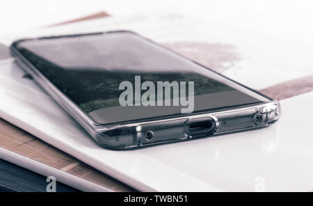 Auf dem Stapel von Zeitschriften ist ein modernes Smartphone. In der Nähe vorgestellt. Stockfoto