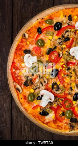 Italienische Pizza mit Schinken, Tomaten und schwarzen Oliven auf Holz, Ansicht von oben, vertikale Panorama Stockfoto