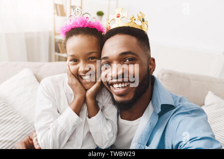 Spielen Prinzessin. Vater und Tochter in Kronen unter Selfie, Spaß zu Hause in Stockfoto