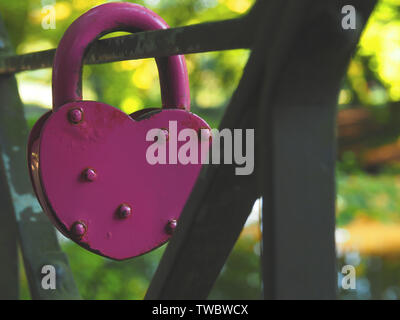 Alten rostigen Rosa herzförmige Vorhängeschloss auf eine Stahlbrücke, aus nächster Nähe erschossen, konzeptionelle Liebe Hintergrund Stockfoto