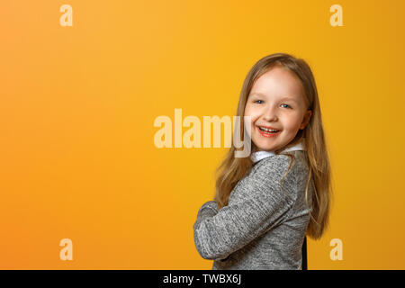 Porträt einer Lustige kleine blonde Mädchen auf einem gelben Hintergrund. Stockfoto