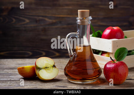 Apfelessig und frischen roten Apfel auf einer hölzernen Hintergrund Stockfoto