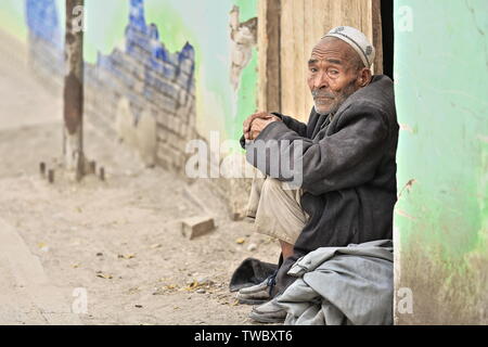 Side Looking Uyghur Old man-sitting on a door Lintel-vieh-Markt-Hotan-Xinjiang-China-0157 Stockfoto