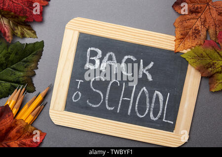 Zurück in der Schule auf einer Schiefertafel mit gelben Bleistifte und Blätter im Herbst auf einer Tafel Hintergrund gedruckt Stockfoto