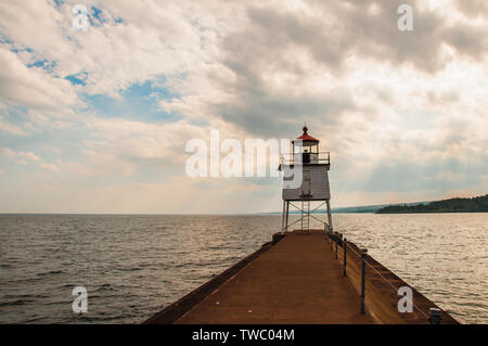 Nahaufnahme der Navigation licht onTwo Häfen Breakwall in Achat Bucht des Lake Superior mit Sonnenlicht durch die Wolken Stockfoto