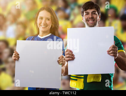 Brasilianische Paar hält weiße Leere Platten auf ein Stadion auf ein Fußball-Spiel, Jubel für Brasilien die Meister zu sein. Stockfoto