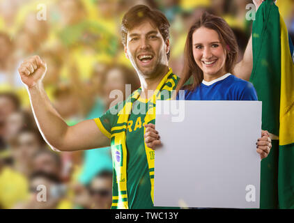 Brasilianische Paar hält weiße Leere Platten auf ein Stadion auf ein Fußball-Spiel, Jubel für Brasilien die Meister zu sein. Stockfoto