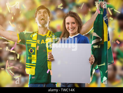 Brasilianische Paar hält weiße Leere Platten auf ein Stadion auf ein Fußball-Spiel, Jubel für Brasilien die Meister zu sein. Stockfoto