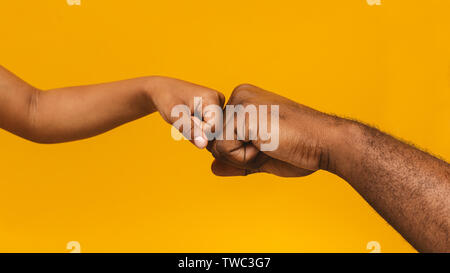 Die Einheit der Familie. Afrikanischer Mann und Mädchen fist Bump, Nahaufnahme, orange panorama Hintergrund Stockfoto