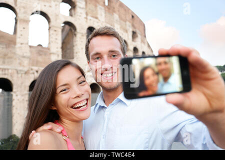 Happy Travel Paar unter selife von Kolosseum, Rom, Italien. Lächelnden jungen romantisches Paar Reisen in Europa, self portrait Foto mit Smartphone Kamera vor dem Kolosseum. Mann und Frau. Stockfoto