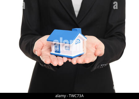 Real estate agent zeigt neue Haus in Mini Größe. Neue hauseigentümer Konzept. Immobilienmakler Übersicht holding Haus Modell. Kauf neuer Home konzeptionelle Bild mit Business woman in Anzug auf weißem Hintergrund Stockfoto