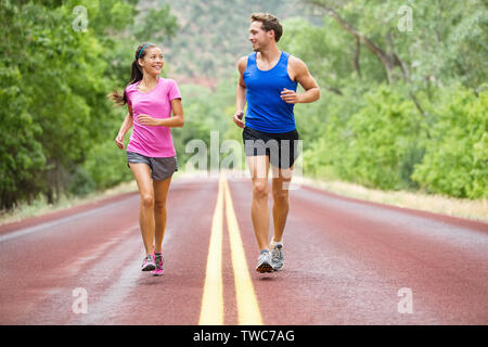 Running-Ausübung Paar joggen und außerhalb sprechen auf der Straße schöne Natur Landschaft. Läufer training zusammen für Marathon laufen. Asiatische Frau sport Frau und Mann fitness Mann in voller Körper. Stockfoto