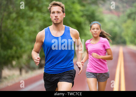 Laufen Paar Joggen auf der Straße. Läufer Training für Marathon laufen Sprint. Aktive junge Gemischtrassiges Paar in Aktiv gesund Lifestyle Konzept. Asiatische Frau und kaukasischen Mann fitness Modell. Stockfoto