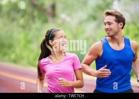 Gesunder Lebensstil - Laufen fitness Paar jogging Lachen, draußen auf der Straße in der wunderschönen Natur. Multirassischen sport Paar, asiatische Frau und Mann fitness Modell Ausübung lächelte glücklich. Stockfoto