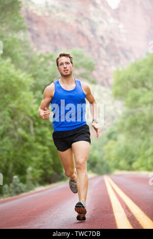 Runner - laufende Athlet Mann. Männliche sprinten, während im freien Training für den Marathon laufen. Sportlich fit Sport Fitness Modell in seinen Zwanzigern in voller Länge auf der Straße draußen in der Natur. Stockfoto