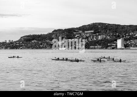 Gruppe von kajakfahrer an Byfjorden, außerhalb der Hafen von Bergen, Norwegen. Große Schiff Statsraad Lehmkuhl im Hintergrund. Stockfoto