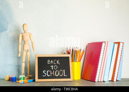 Komposition mit Schulmaterial auf grau Tabelle gegen hellen Hintergrund Stockfoto