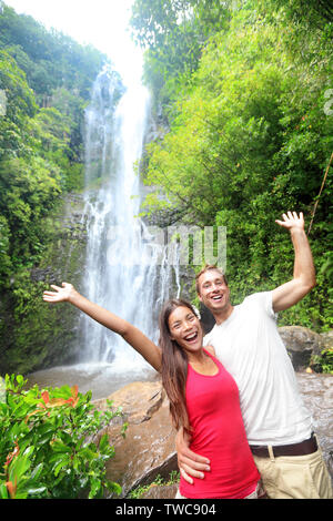 Hawaii touristische Menschen Paar von Wasserfall gerne während der Fahrt auf der berühmten Strasse nach Hana auf Maui, Hawaii. Ökotourismus Konzept Bild mit glücklichen Backpackers. Interracial Asiatischen/Kaukasischen jungen Paar. Stockfoto