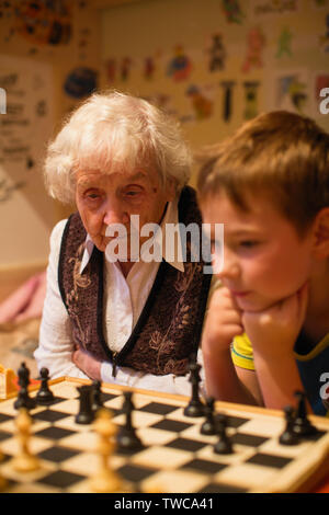 Eine alte Dame ist Schach spielen mit Ihrem kleinen Enkel. Stockfoto