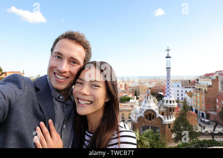 Happy Travel Paar im Park Güell, Barcelona, Spanien. Schöne junge Gemischtrassiges Paar an der Kamera unter selfie Lächeln freuen sich über Europa Urlaub Reise suchen. Asiatische Frau, kaukasische Mann. Stockfoto