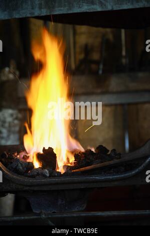 In der Nähe von Flammen mit männlichen Schmiede bei der Arbeit machen Metall Formen in seiner Schmiede Workshop, Hillsboro, Wisconsin, USA. Stockfoto