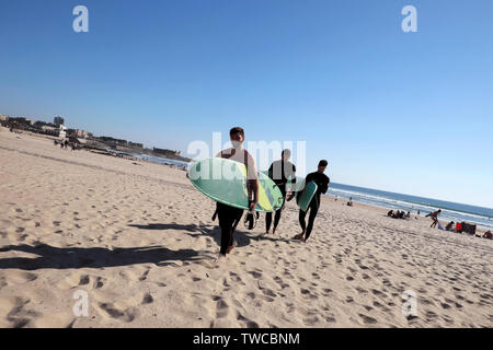 Junge Männer, die surfbretter in der Frühlingssonne zu Fuß am Sandstrand im Matosinhos Porto Portugal Europa EU-KATHY DEWITT Stockfoto