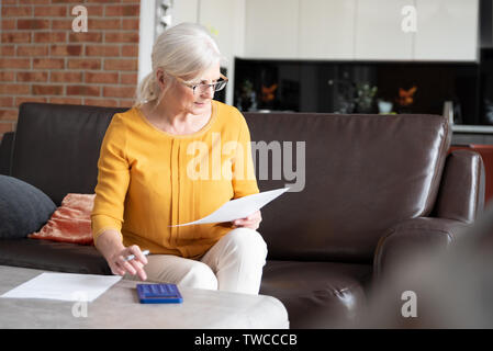 Ältere Frau mit Taschenrechner und Rechnungen zu zählen. Finanzen, Einsparungen Konzept Stockfoto