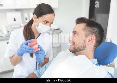 Weiblichen Zahnarzt Haltebacken proben Zahn mit Klammern Modell. Professionelle zahnmedizinische Klinik. Stockfoto