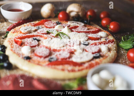 Kochen Pizza mit Tomaten, mit geriebenem Käse close-up. Stockfoto