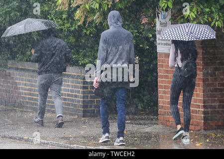Die Menschen Schutz vor dem Regen unter Sonnenschirmen während der schweren Regenguß in London Stockfoto