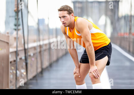 Laufender Mann Ausruhen nach in New York City ausgeführt. Runner Training und Joggen außerhalb eine Pause. Kaukasische männliche Läufer und Fitness Sport Modell auf der Brooklyn Bridge, New York City, USA. Stockfoto