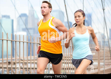 Laufen Paar joggen Training für den New York Marathon. Läufer auf Ausführen. Asiatische Frau und kaukasischen Mann runner und Fitness Sport Modelle Joggen auf der Brooklyn Bridge, New York City, USA. Stockfoto