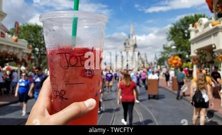 Mit einem Starbucks Tasse in Walt Disney World mit der Burg im Hintergrund und Hauptstraße. Stockfoto