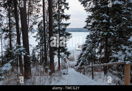 Winter Holztreppe hinunter zur Bootsanlegestelle am See Stockfoto