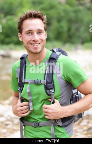 Aktiver mann Portrait von sportlichen Kerl wandern im Freien. Junge männliche Wanderer glücklich lächelnd in die Kamera tragen Rucksack im Freien während der Wanderung im Wald Natur. Kaukasische männlichen Modell außerhalb. Stockfoto