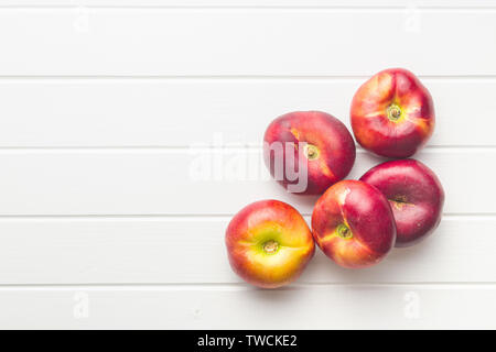 Flache Nektarinen auf weißen Tisch Reif. Ansicht von oben. Stockfoto