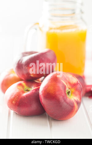 Flache Nektarinen und Saft Glas auf weißen Tisch Reif. Stockfoto