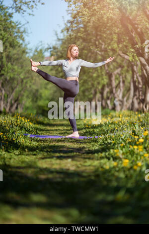 Bild der Frau an der Seite des Stehen auf einem Bein Üben Yoga im Wald suchen Stockfoto