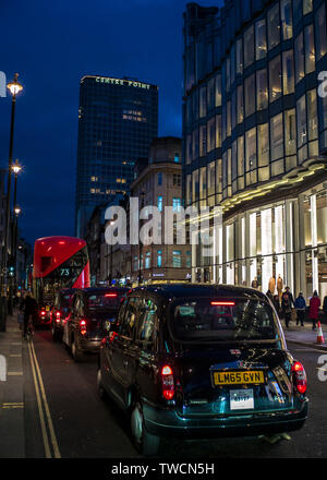 Schwarze Taxis und London Doppeldeckerbus Oxford Street bei Nacht mit Mittelpunkt Turm im Hintergrund Stockfoto