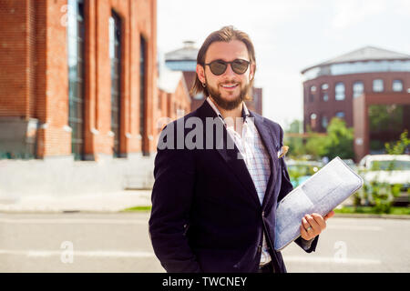 Foto von glücklichen Menschen in Sonnenbrille und Jacke mit Laptop in der Stadt im Frühjahr Stockfoto