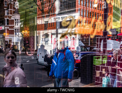 Mehrere Reflexionen von einer geschäftigen Stadt im Schaufenster. Stockfoto