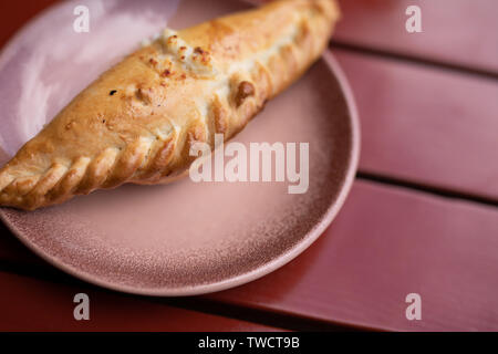 Kibinai, traditionelle litauische Essen, Gebäck mit süßem Quark gefüllt, beliebt bei Karaite ethnische Minderheit in Trakai, Litauen. Red backgr Stockfoto