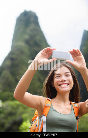 Frau Wanderer unter selfie Foto mit Smartphone beim Wandern auf Hawaii Genießen Aktivitäten im Freien. Frau Wanderer unter Foto mit smart phone Kamera. Iao Valley State Park, Wailuku, Maui, USA. Stockfoto