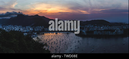 Panoramablick auf Rio de Janeiro bei Sonnenuntergang. Boot sitzt in den Hafen und die Strände der Bucht unter dem Christus der Erlöser Statue, Brasilien Bend Stockfoto