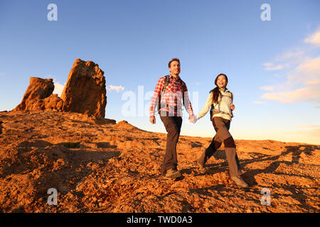 Wanderer Wandern in einer wunderschönen Landschaft. Wandern Paar Mann und Frau trekking Wandern mit Rucksäcken in Trail bei Sonnenuntergang in den Bergen von Roque Nublo, Gran Canaria, Kanarische Inseln, Spanien. Stockfoto