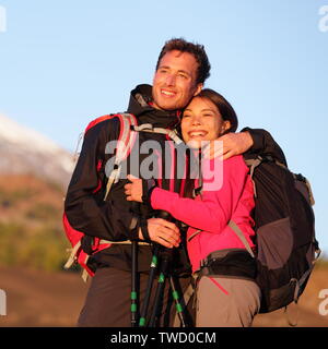 Romantisches Paar umarmen Wandern aktiven Lebensstil in der Liebe. Wanderer, Mann und Frau tragen Rucksäcke Sonnenuntergang während der Wanderung auf den Berg. Stockfoto