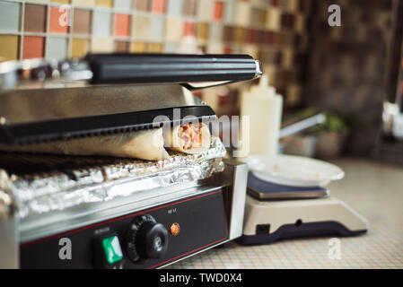 Shawarma Döner gebacken in einem elektrischen Ofen in einem Fast Food Restaurant. Kochen pita und Ciabatta auf dem Grill. Stockfoto